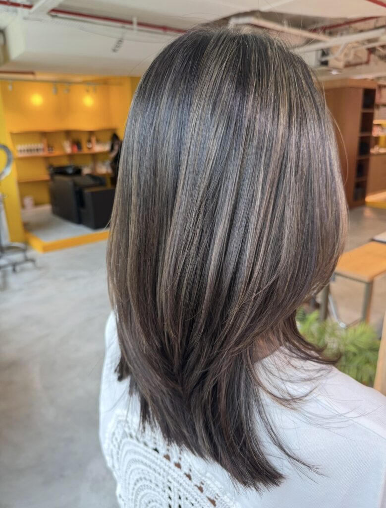 Ash grey blending highlights on layered medium-long hair at Colors Japanese Hair Salon Singapore near Clarke Quay MRT, Chinatown and Havelock Road, creating cool-toned dimension and seamless white hair grow-out.