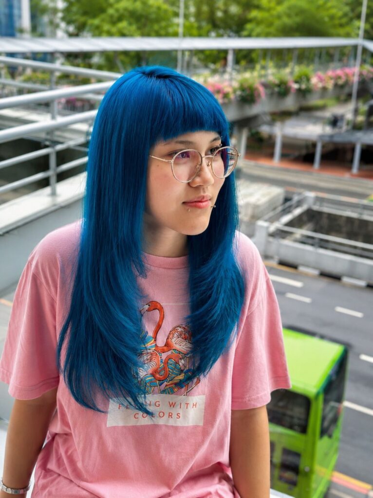 Vivid blue hair color with face-framing layers and low-damage bleach by Creative Stylist Carmen at Colors Japanese Hair Salon Singapore.