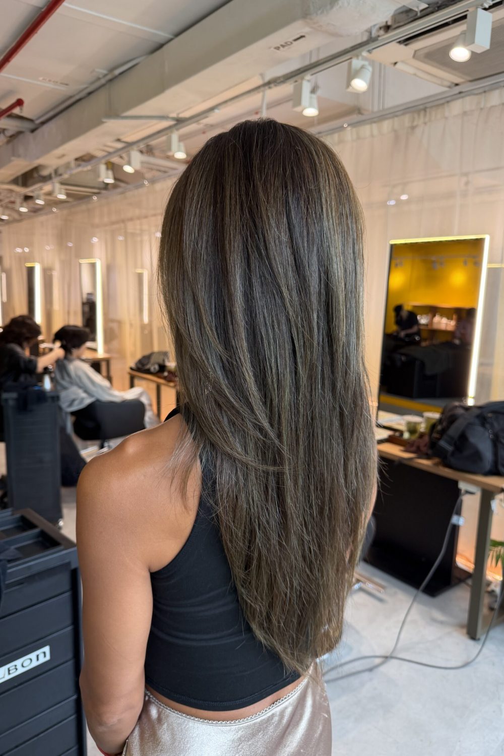 Long high layer haircut with olive ash grey coverage at Japanese Hair Salon Singapore. Low-damage Plex color keeps hair bright while naturally blending grey hair with healthy shine.