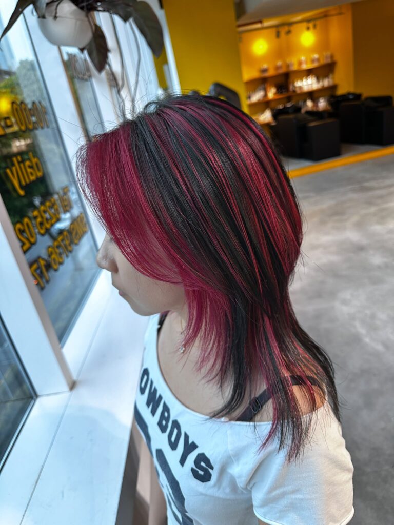 Medium layered haircut with vivid red design bleach color on a natural dark base. Japanese layer cut featuring random bleach placement, low-damage Plex bleach, and vibrant fashion hair color at Colors Japanese Hair Salon Singapore.