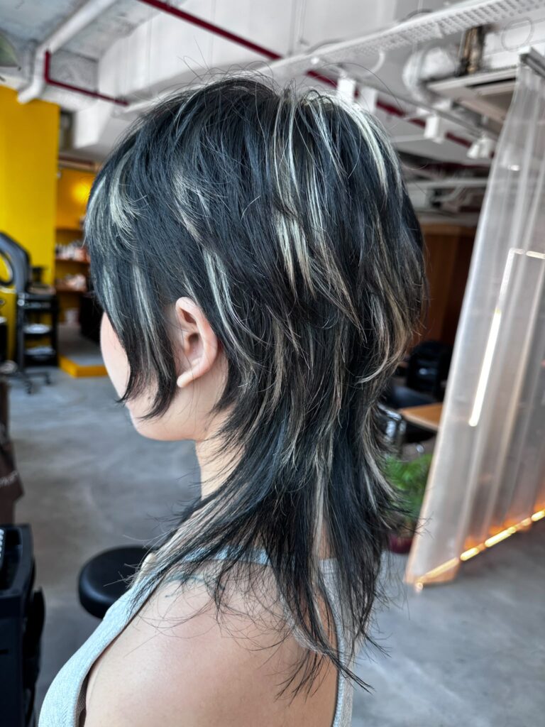 Medium high layer haircut with contrast blonde highlights. Japanese high layer style featuring long nape, natural movement, and low-damage bleach highlights at Colors Japanese Hair Salon Singapore.