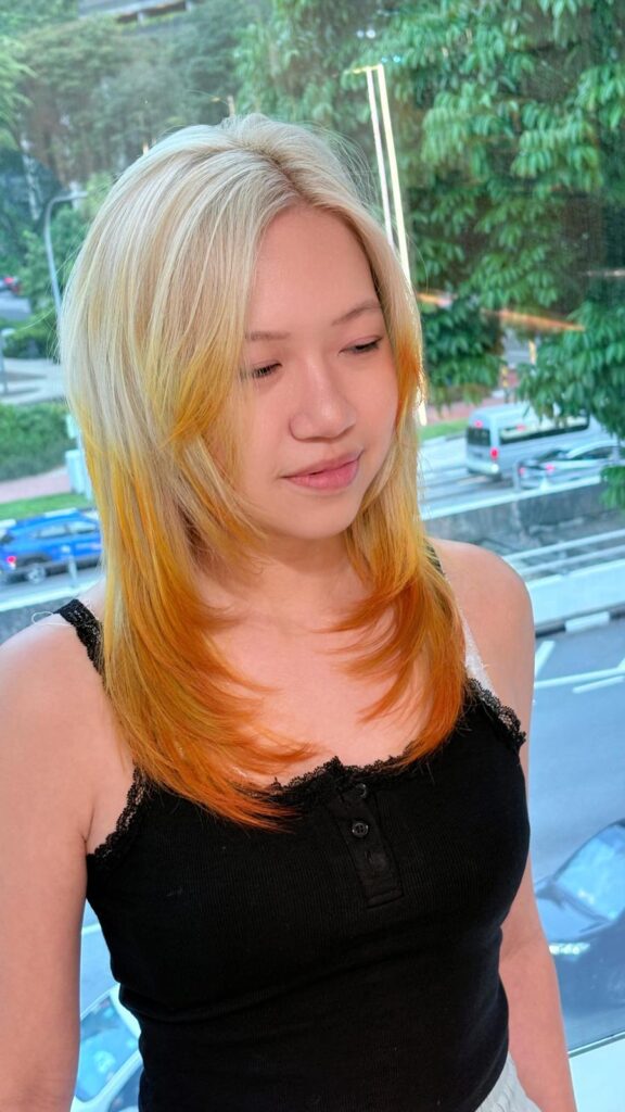 Yellow Blonde Long Layers with Orange Design Color in Singapore 1 Long layered hair with face-framing layers, yellow blonde base and vivid orange design color at a Japanese hair salon in Singapore.
