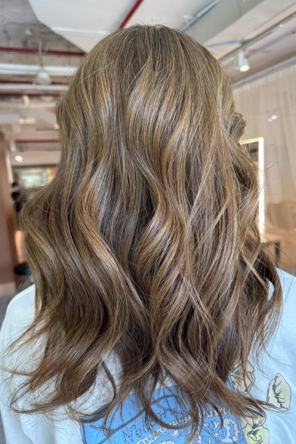 Long layered hair with a V-shaped back silhouette and bright honey brown grey coverage, designed to keep movement, shine and a softer regrowth line at a Japanese hair salon in Singapore.
