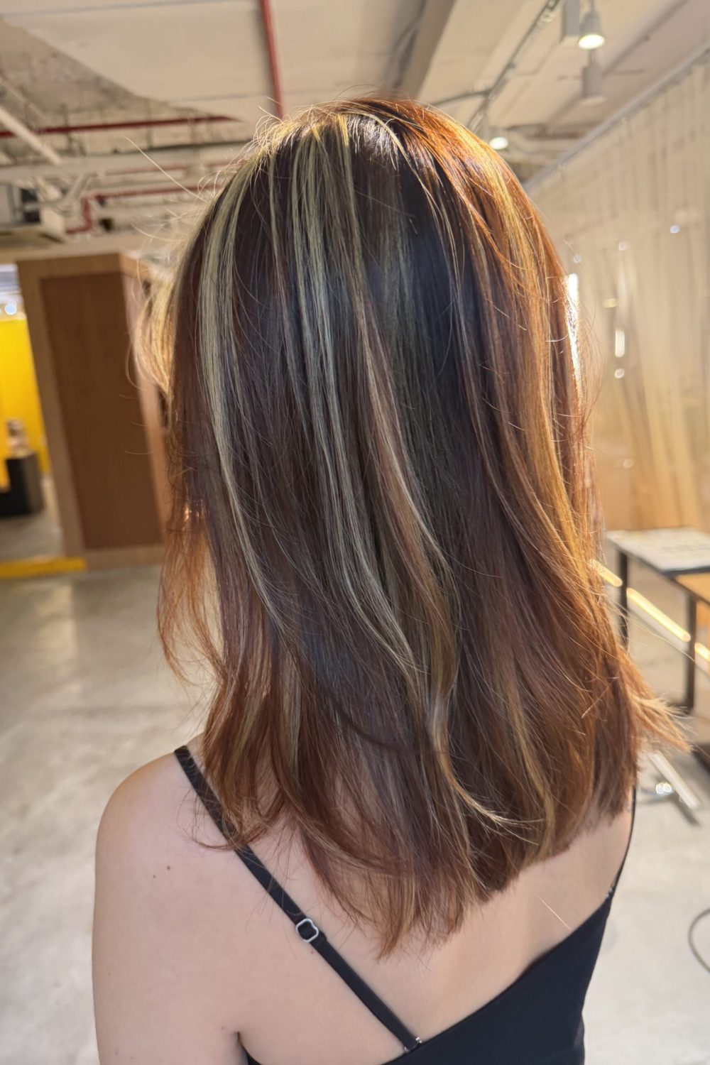 Medium layered hair with yellow blonde and dark copper highlights, created with Plex-supported color and bleach highlights in Singapore