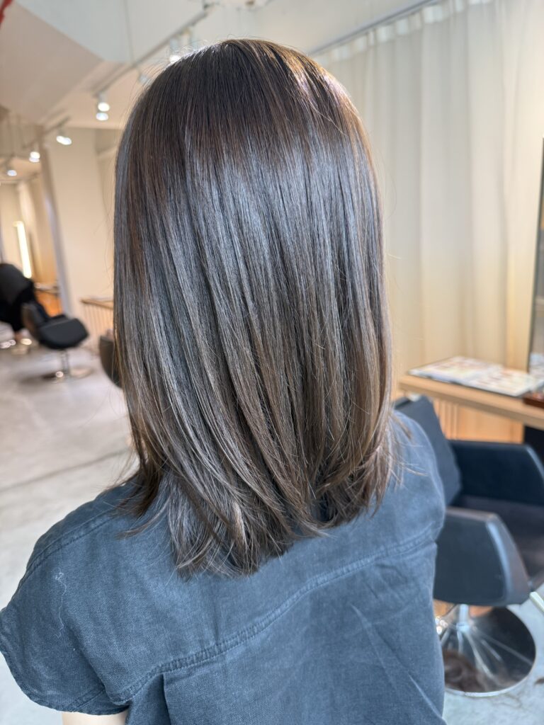 Medium low layer haircut with olive hair color in Singapore designed to reduce red undertones for thick hair at a Japanese hair salon.