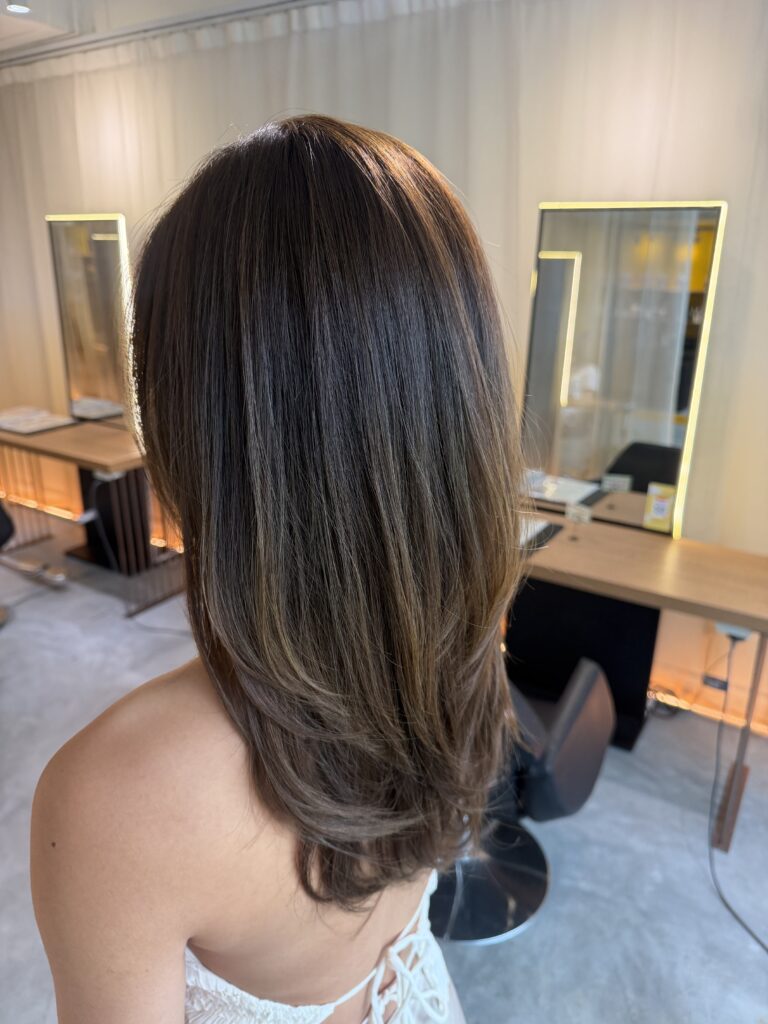 Long layered haircut with face framing layers and monotone hair color in Singapore for softer movement and brighter hair without bleach at a Japanese hair salon.