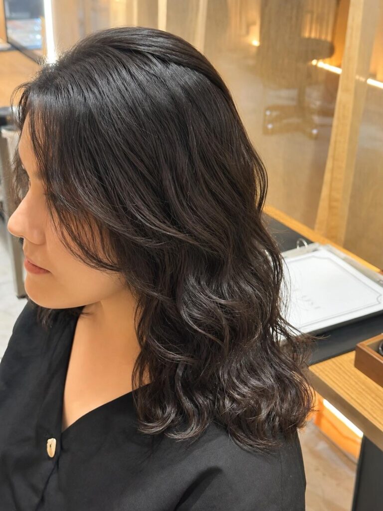 Medium black hair with digital perm, face-framing layers and soft voluminous curls at a Japanese hair salon in Singapore.