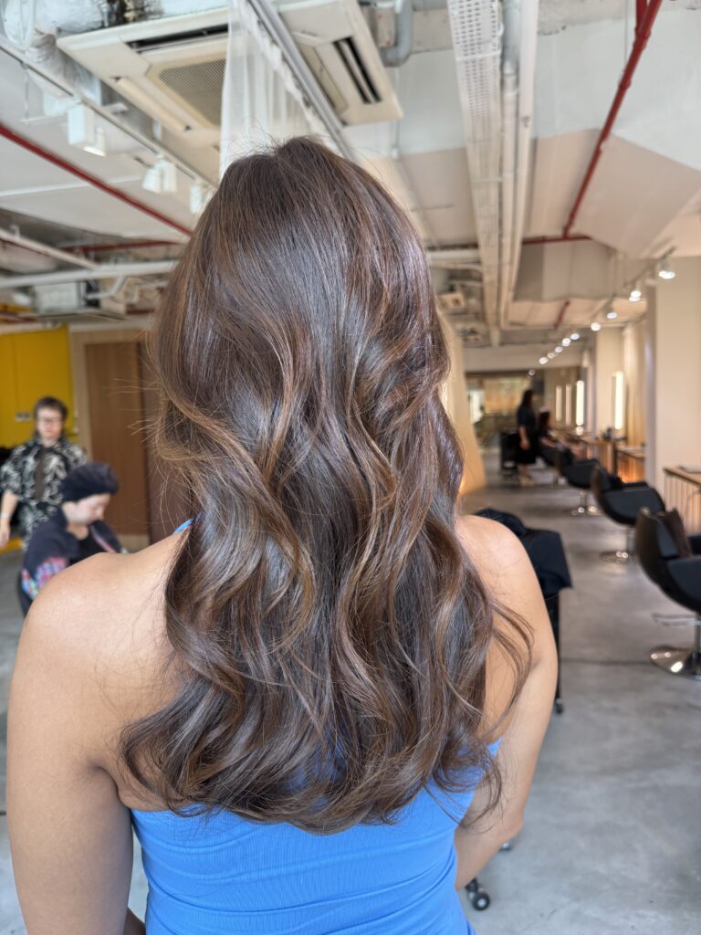 Long heavy-layered hair with bleach-free camel brown Plex color and soft curled styling at a Japanese hair salon in Singapore.