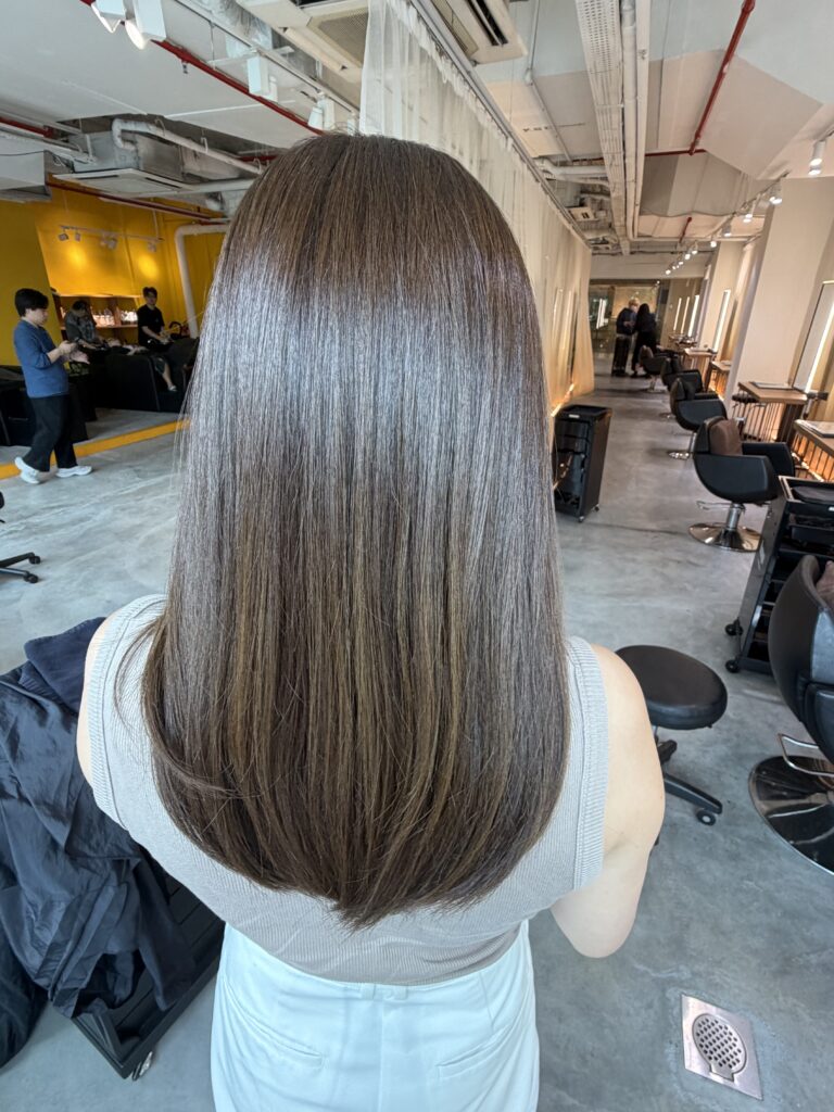 Long olive brown hair with Plex color, a heavy silhouette and glossy finish at a Japanese hair salon in Singapore.