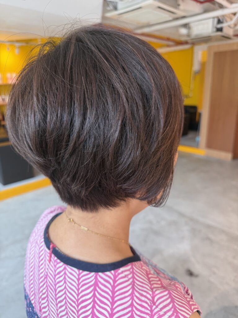 Warm Brown Grey Coverage with Asymmetrical Short Hair in Singapore 1 Asymmetrical short haircut with full grey coverage in warm brown, featuring a neat nape and volume at the top at a Japanese hair salon in Singapore.