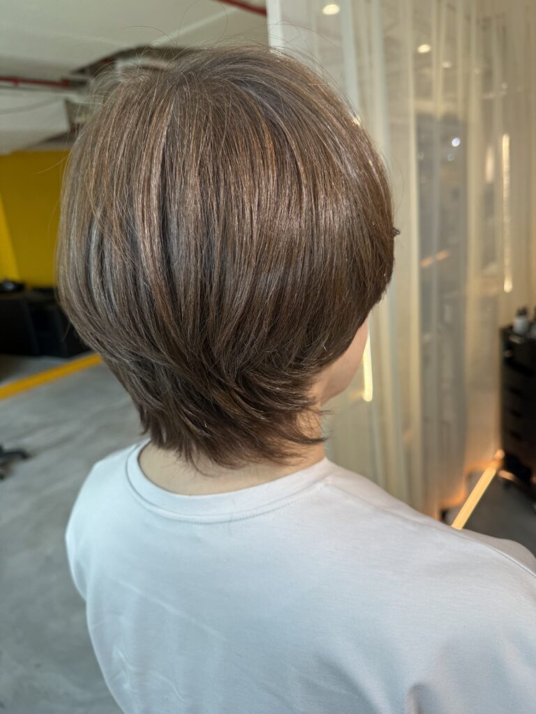 Short layered haircut with bright grey coverage in warm beige brown at a Japanese Hair Salon Singapore, featuring natural volume, longer nape design, and low-damage Plex hair color for seamless grey blending.