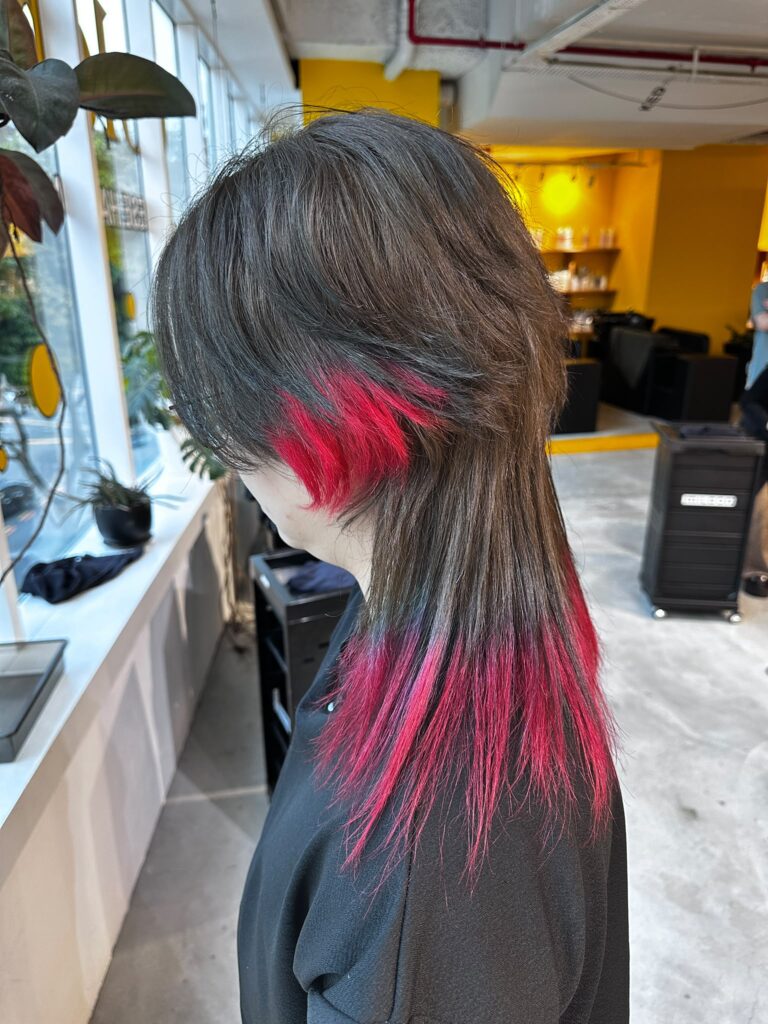 Long high-layer jellyfish cut with vivid red bleach design on the ends, featuring a disconnected layered shape and bold contrast color in Singapore