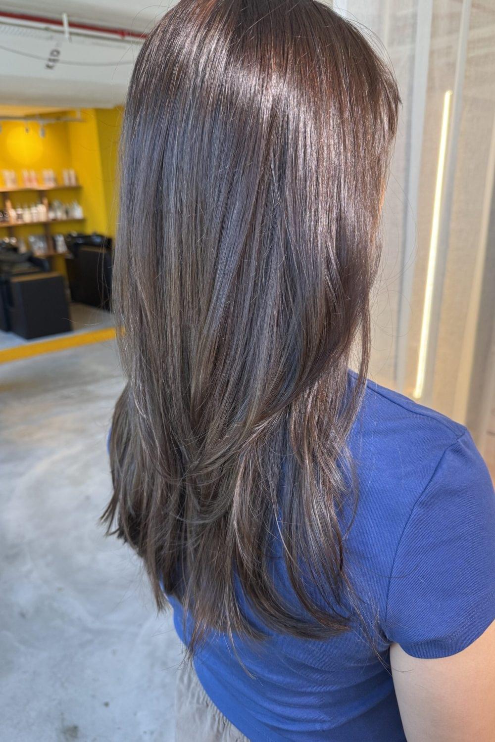Dark ash brown long layered hairstyle with glossy low-damage color by Stylist Satsuki and Colorist Ura at Colors Japanese Hair Salon Singapore.