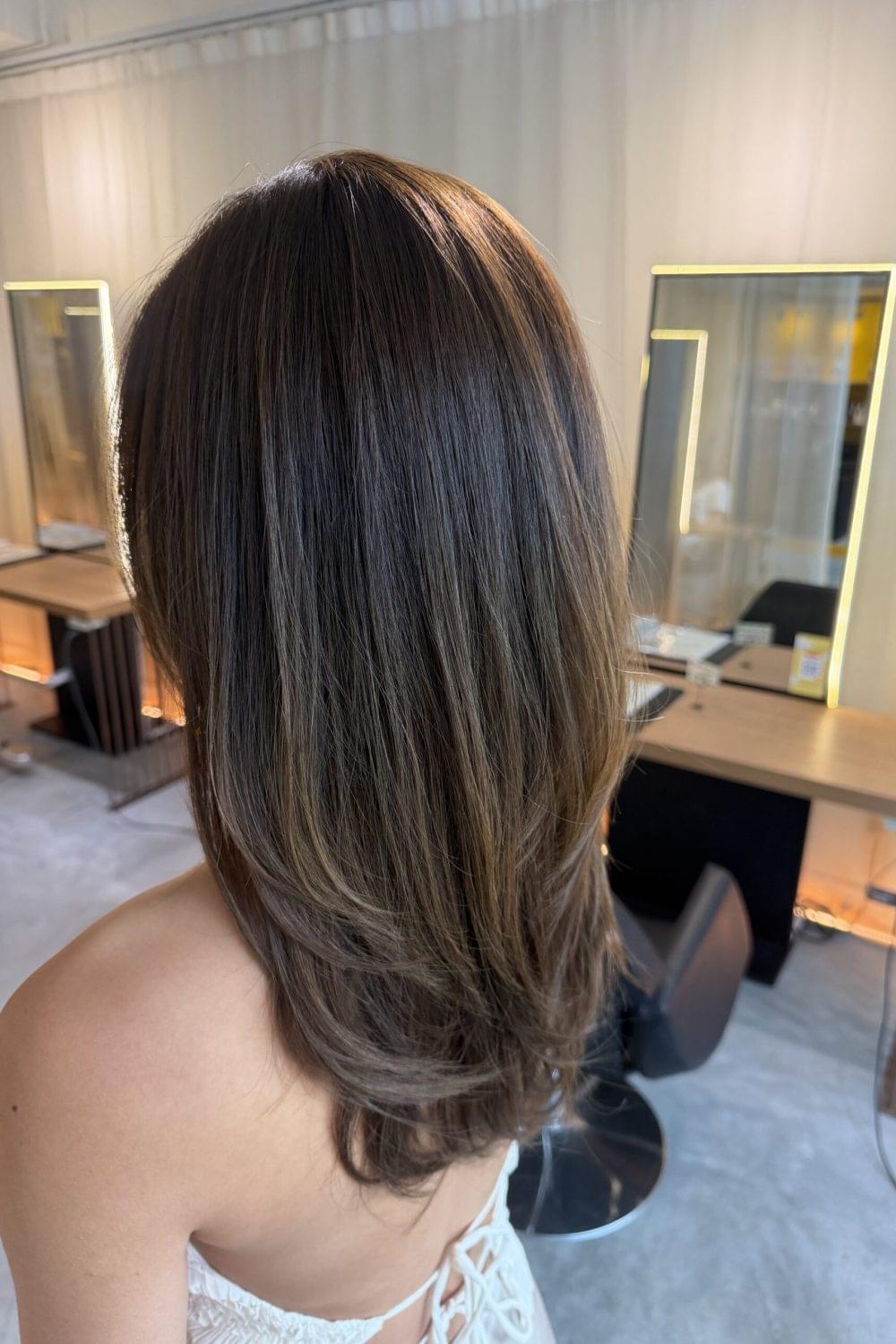 Long layered ash beige hairstyle with face-framing layers and soft natural shine by Stylist Satsuki and Colorist Ura at Colors Japanese Hair Salon Singapore.