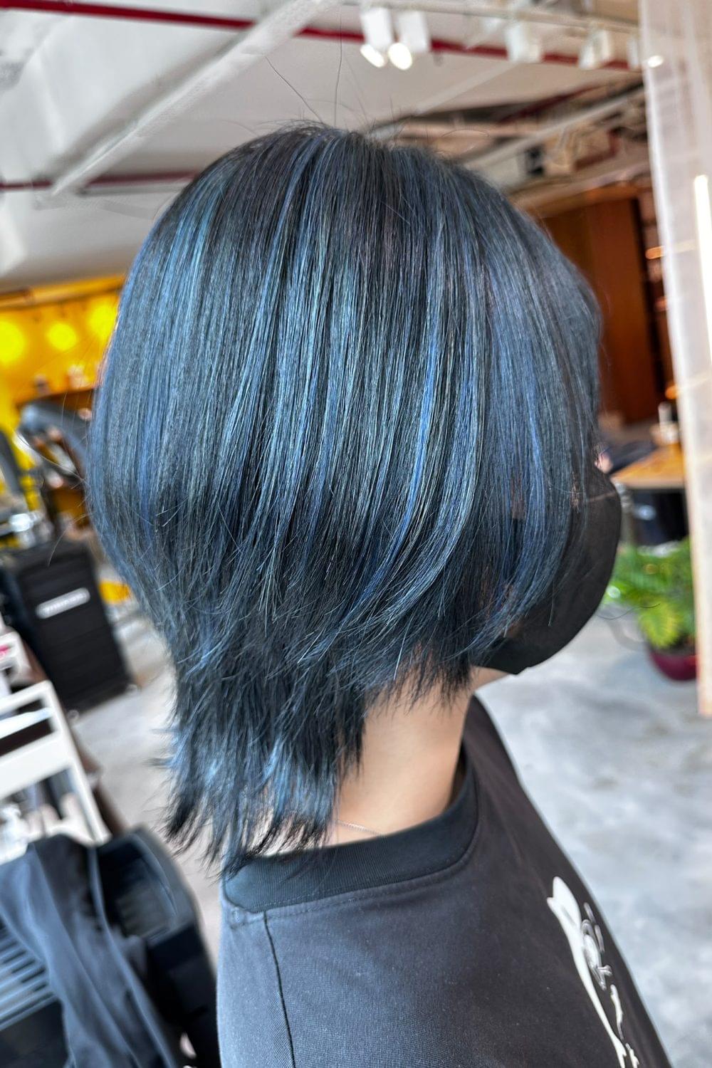 Medium layered wolf cut with blue silver bleach highlights, creating volume, movement, and a rounded shape at the back with low-damage Plex-supported color in Singapore