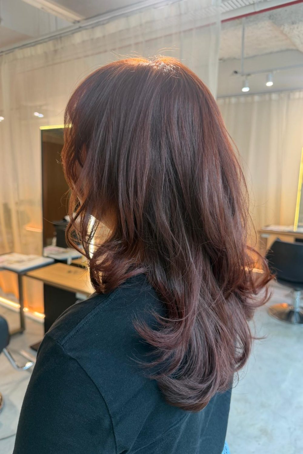 Medium layered pink red hair without bleach at Colors Japanese Hair Salon Singapore. Japanese hair salon Singapore specializing in low-damage plex color, medium layer cut, natural volume, and hair color for wavy hair near Clarke Quay.