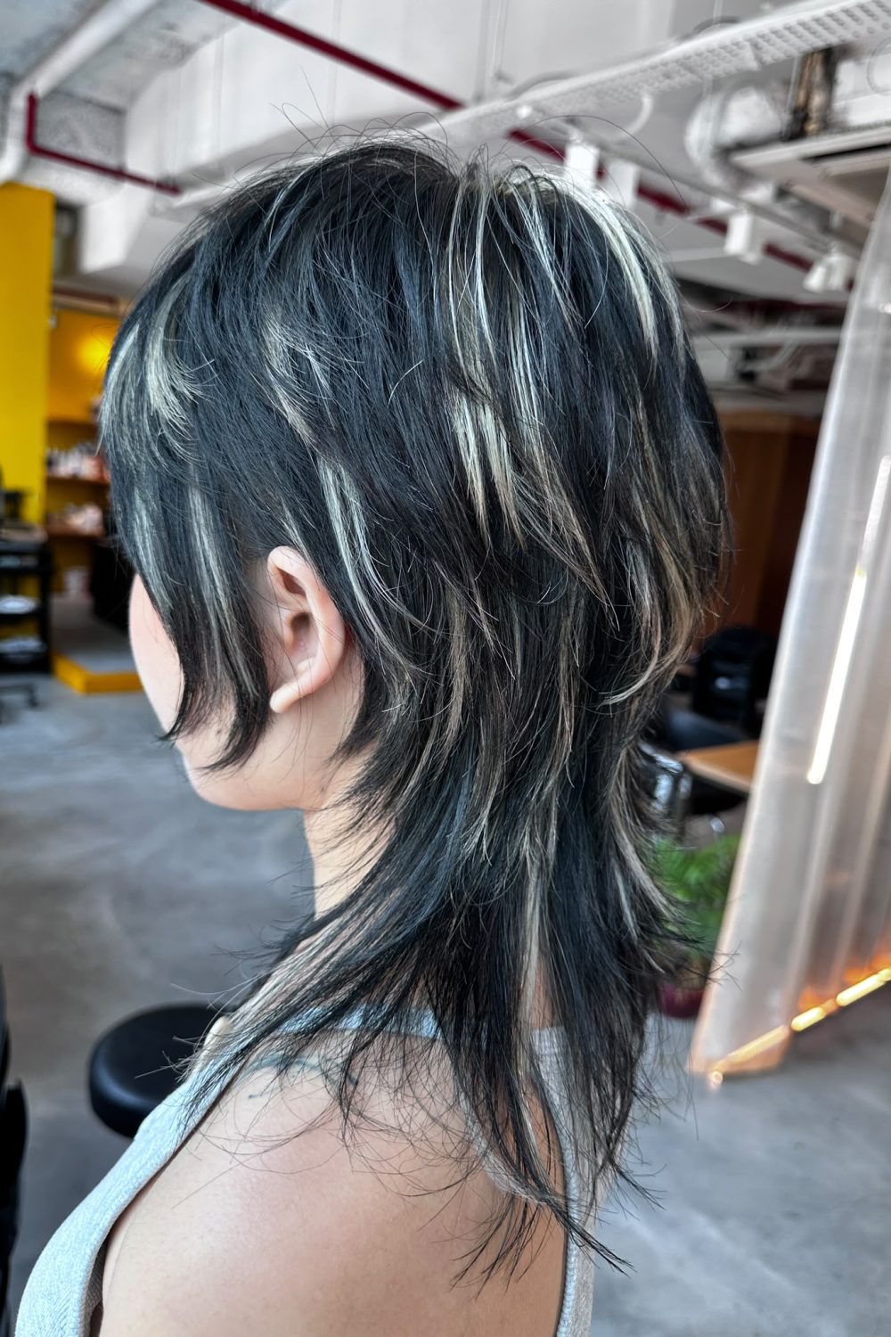 Medium high layer haircut with contrast blonde highlights. Japanese high layer style featuring long nape, natural movement, and low-damage bleach highlights at Colors Japanese Hair Salon Singapore.