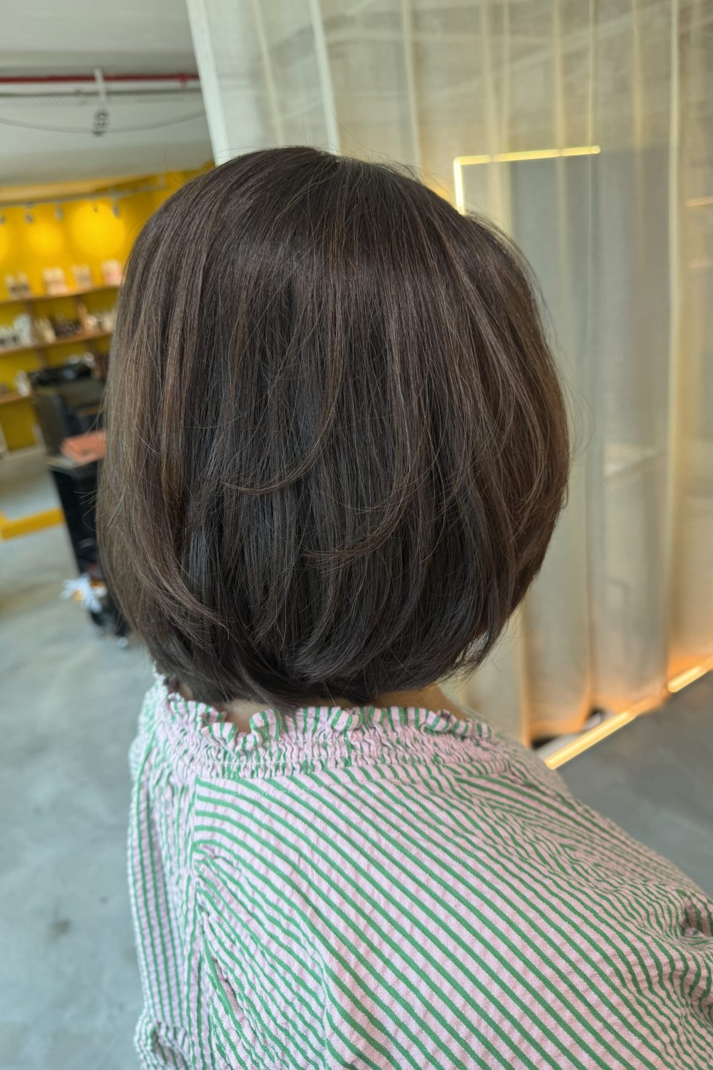 Back view of a layered bob with ash brown hair color created without bleach using Plex Color at a Japanese Hair Salon Singapore, featuring natural shine, soft movement, and a healthy low-damage finish.