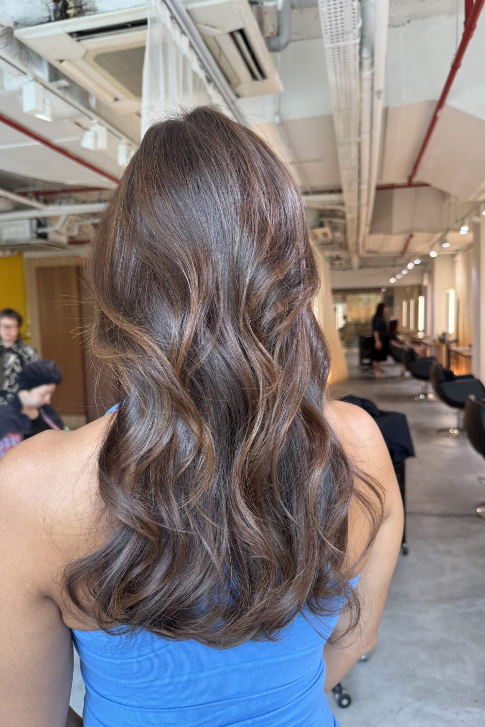 Long heavy-layered hair with bleach-free camel brown Plex color and soft curled styling at a Japanese hair salon in Singapore.