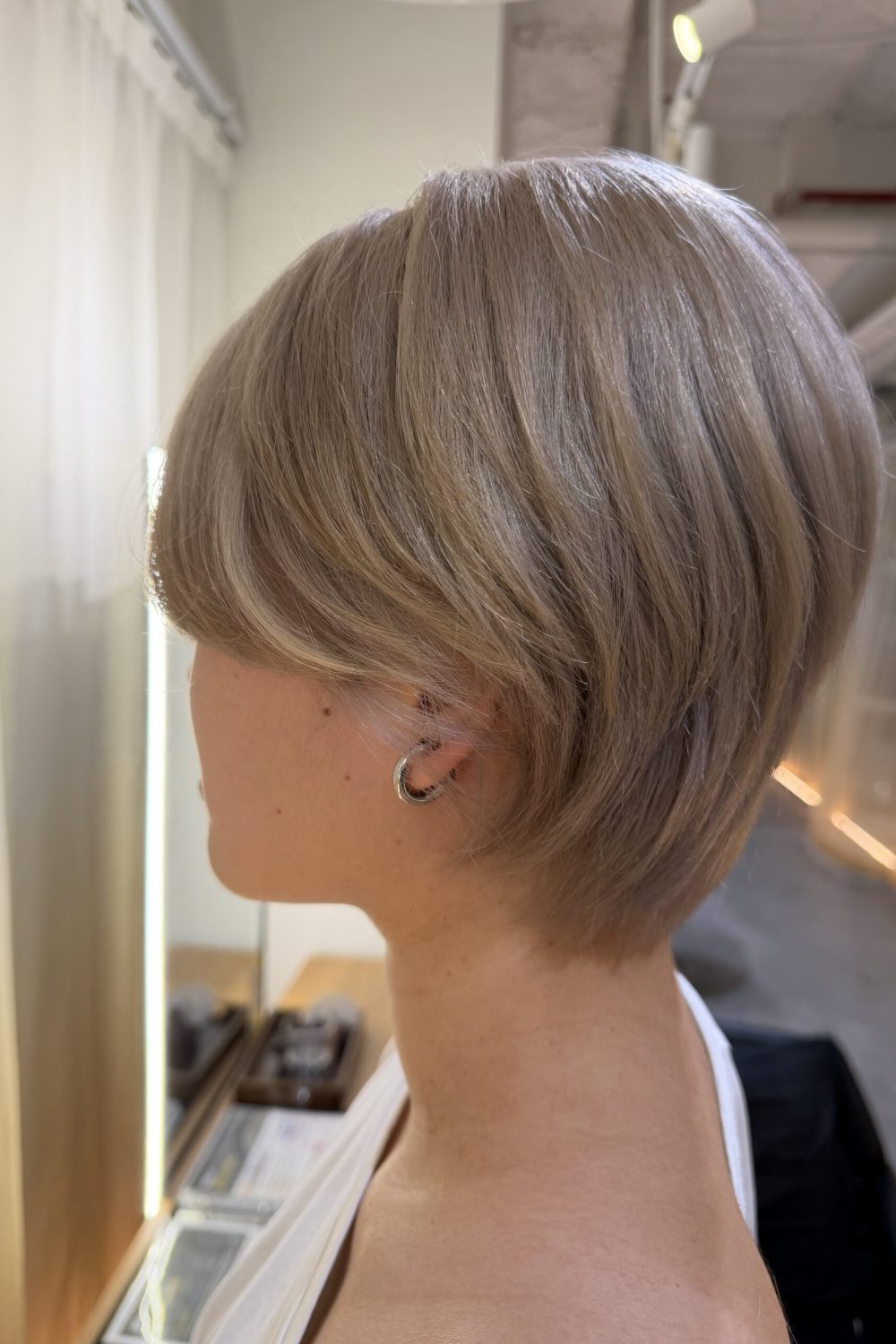 White beige short layered hair with Plex bleach at a Japanese Hair Salon Singapore, featuring a soft neckline and cheek-length face-framing bangs.