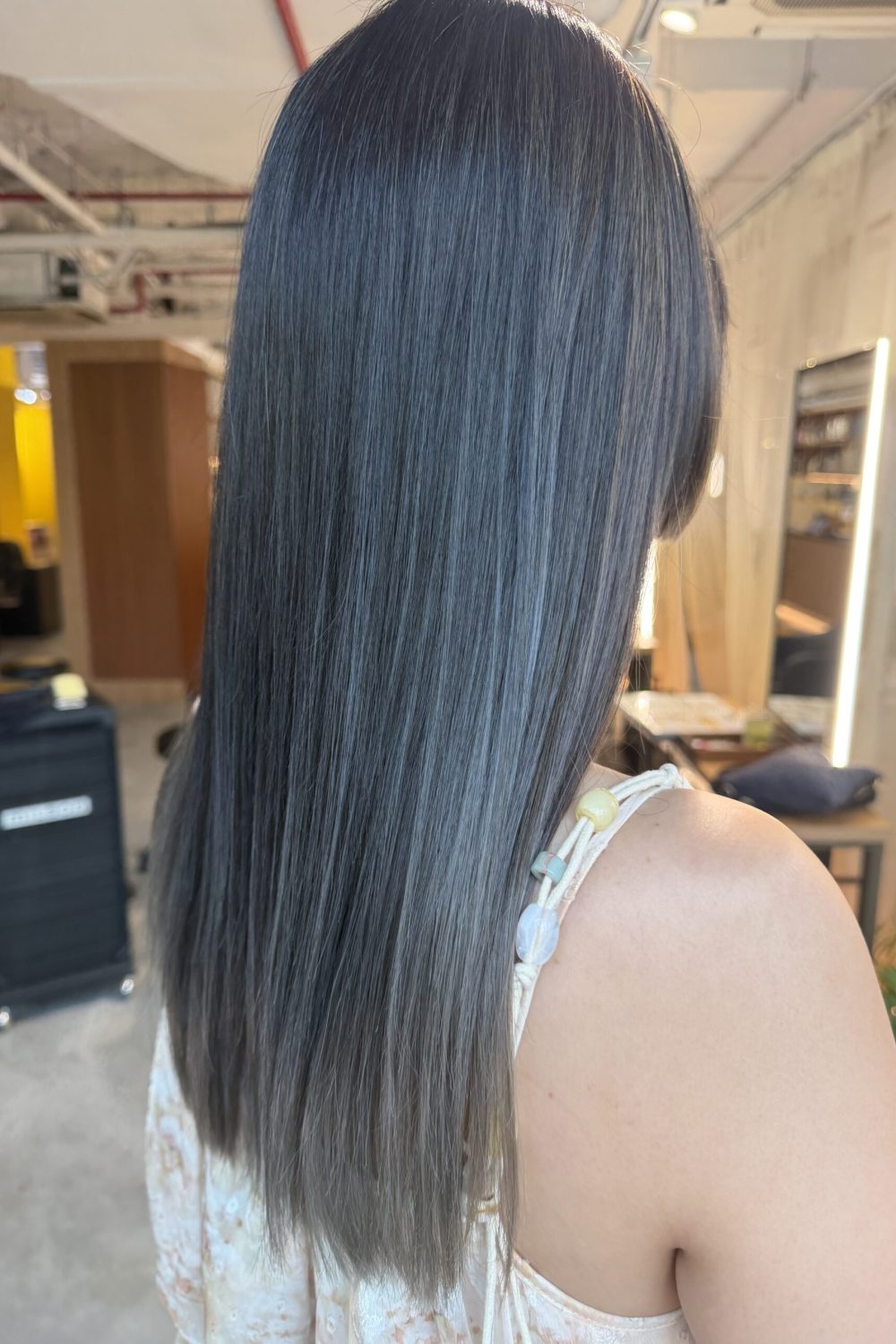 Long hair transformed from previously red hair into an AirTouch silver gradient color with a dark ash base, hime bangs and a heavy layered-free silhouette at a Japanese hair salon in Singapore.