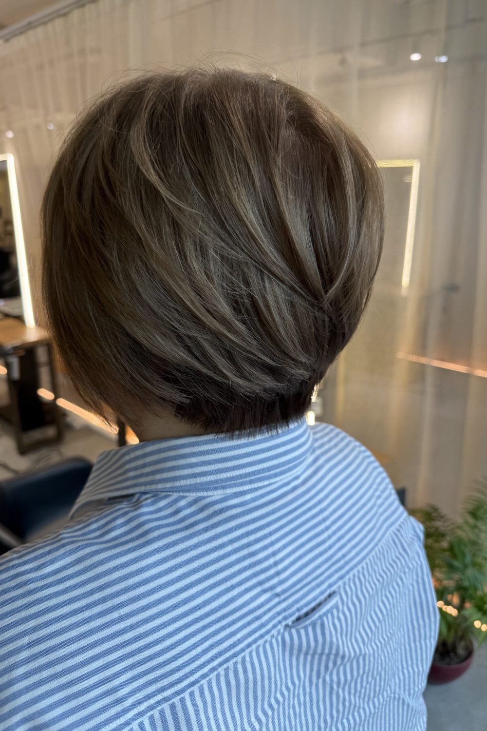 Grey blending highlights on a short graduation bob with ash beige tones. Fine bleach highlights soften grey hair while maintaining a natural look. Japanese precision haircut with excellent nape shaping at Colors Japanese Hair Salon Singapore.