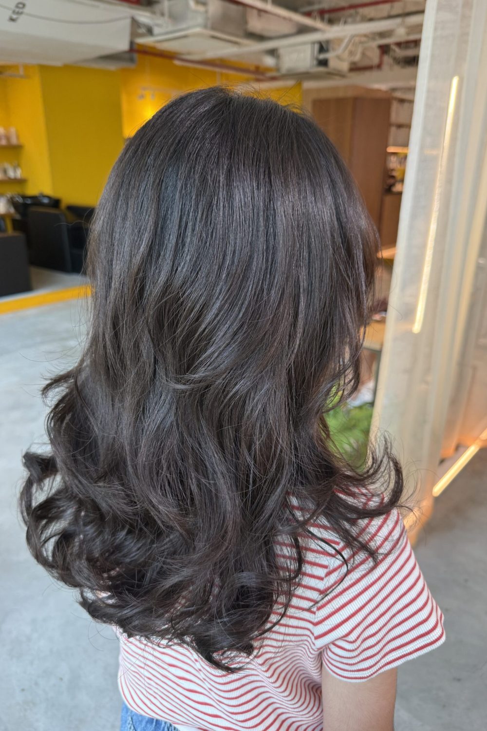 Long straight virgin hair transformed with a digital perm and layered cut, creating soft curls and movement with Plex-supported care in Singapore