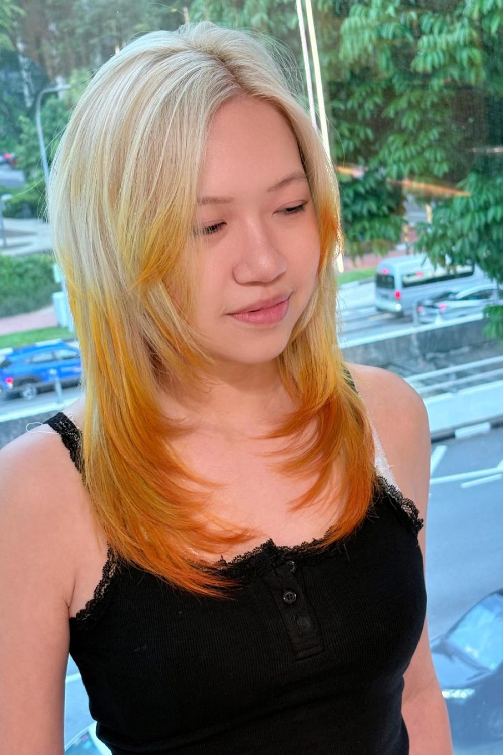 Long layered hair with face-framing layers, yellow blonde base and vivid orange design color at a Japanese hair salon in Singapore.