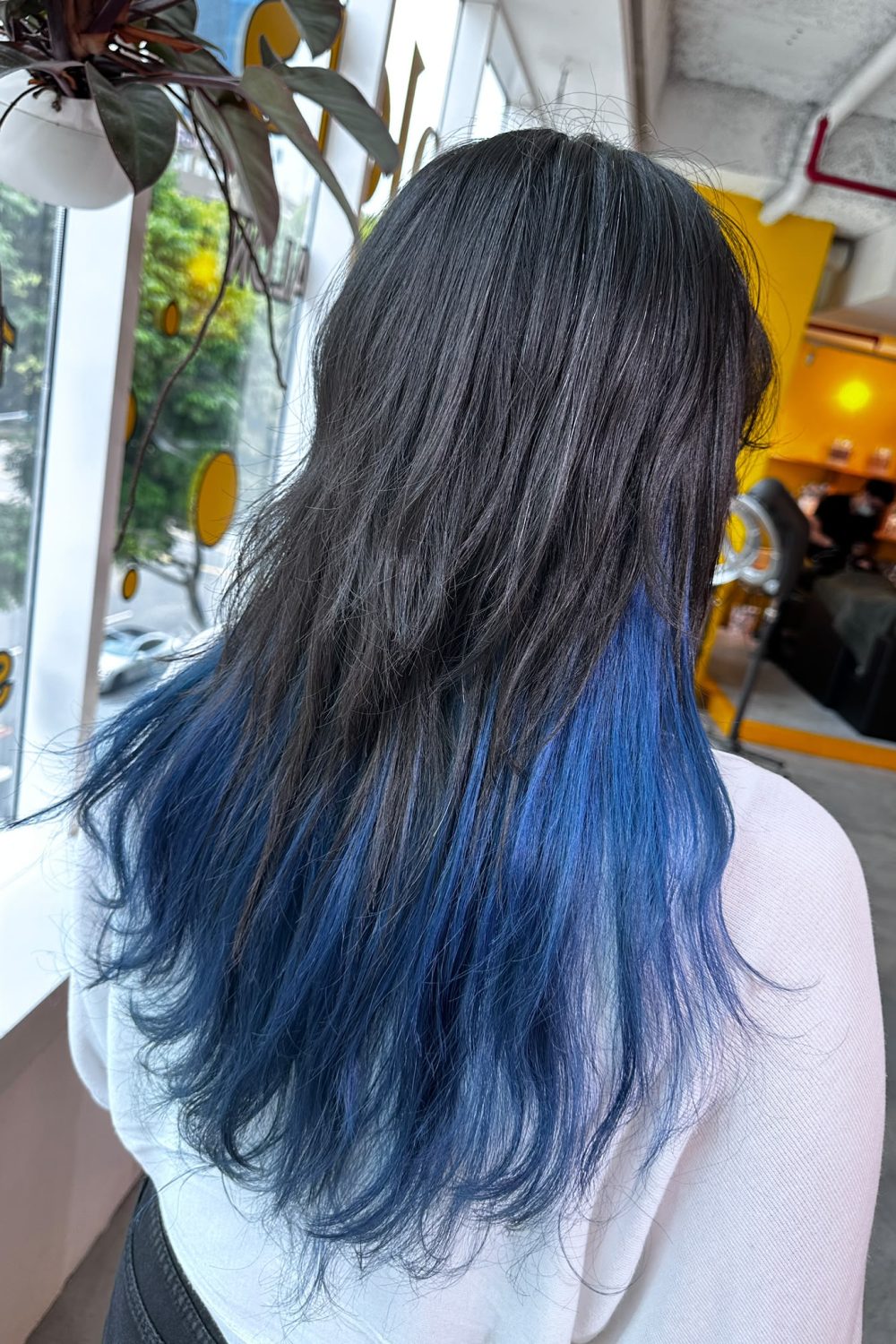 Long high-layer haircut with vivid blue inner color in Singapore. The hidden bleach design enhances movement while Plex protection minimizes damage for healthier hair.